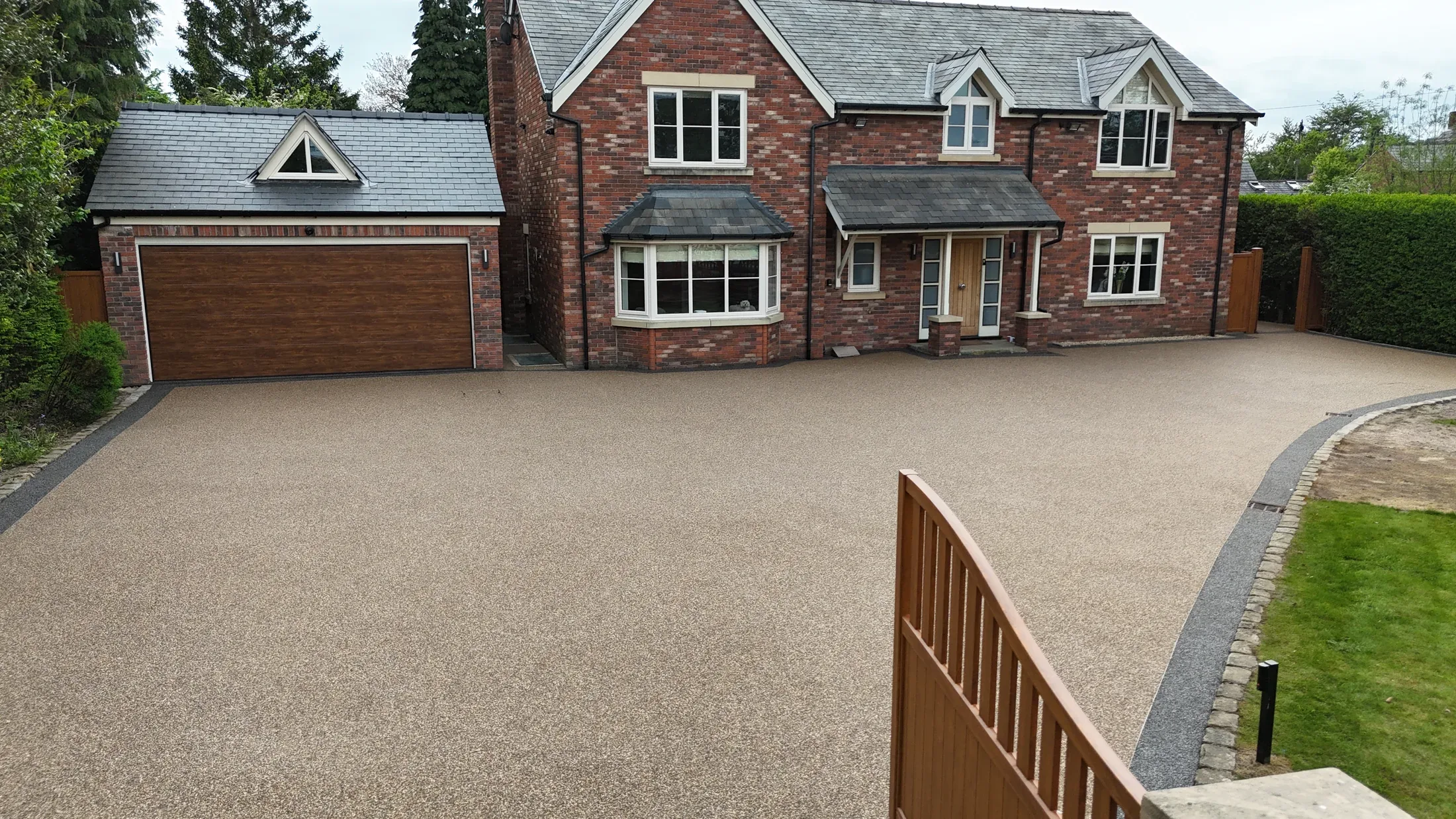 Large finished warm resin bound driveway with dark edging outside a Cheshire home