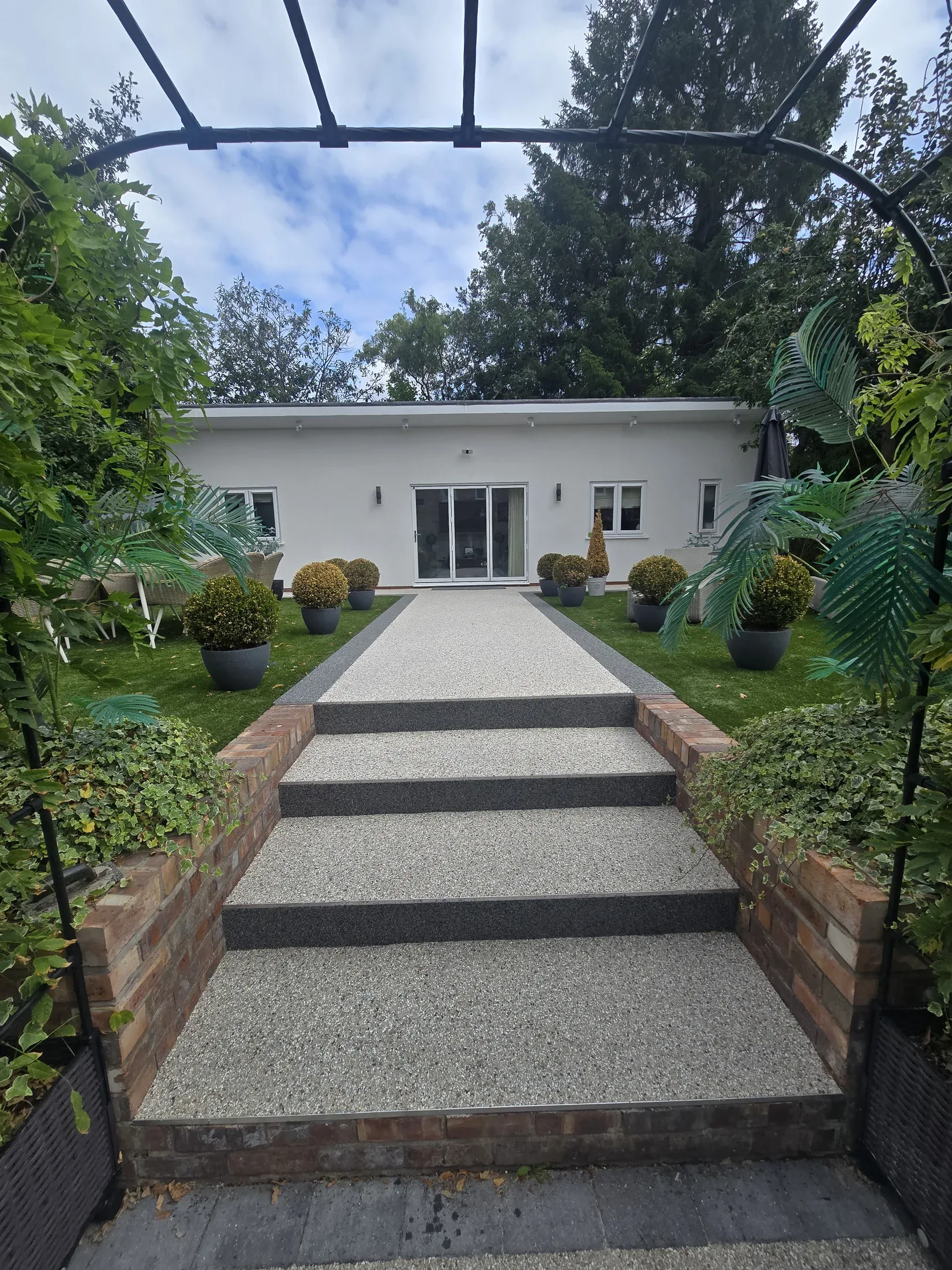 A pale resin path and broad garden steps leading to a Cheshire home