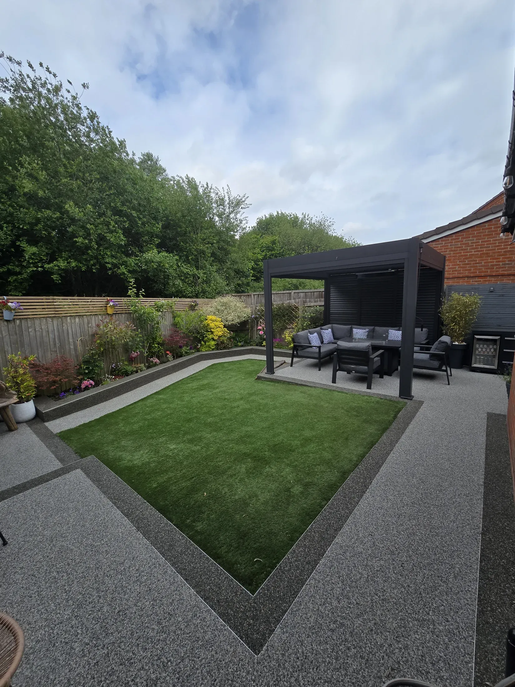 Two-tone resin patio and path surrounding a neatly landscaped garden